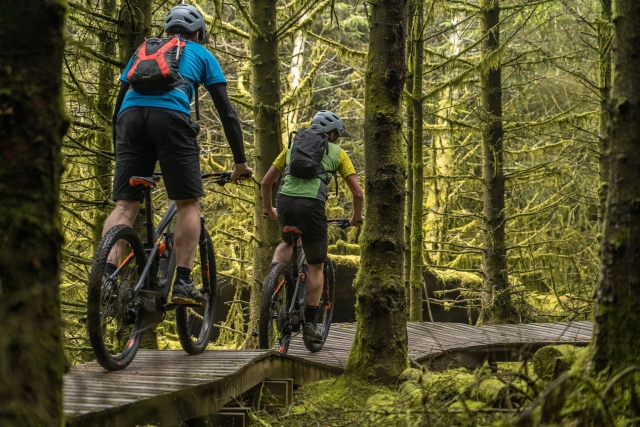 Deux coureurs portant des sacs à dos et des casques lors de leur expérience de vélo de montagne en forêt 