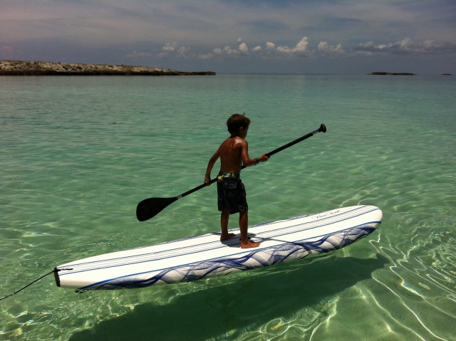 Boy with a wonderful tan paddleboarding over white board