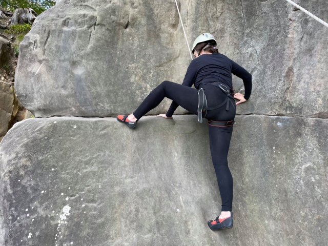 Femme portant des vêtements noirs et un casque blanc lors de son expérience d'escalade en groupe 