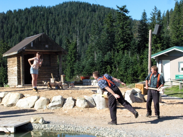Two men in the middle of the forest doing axe throwing
