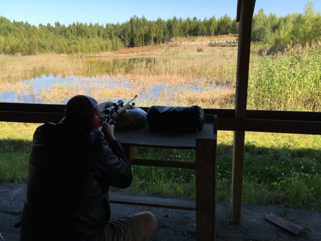  Mann beim Schießen mit Schutzausrüstung und der Wald vor ihm 