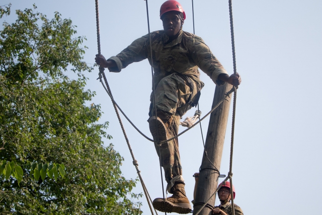 Homme portant un casque rouge et une combinaison de camouflage pendant son aventure en haute corde 