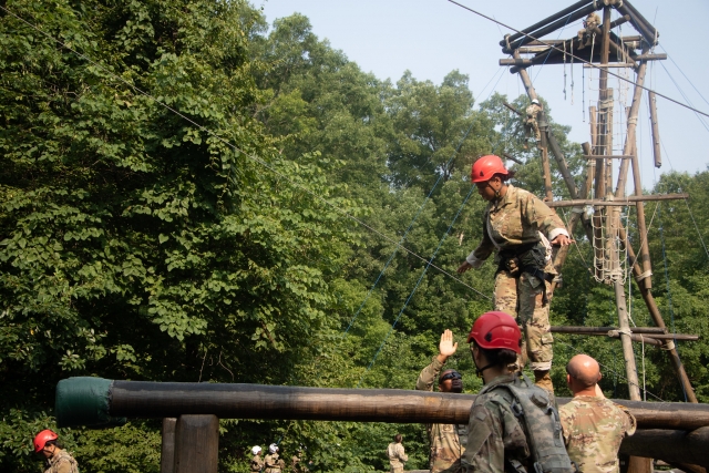  Homme portant un casque rouge et une combinaison de camouflage traversant un obstacle en bois 