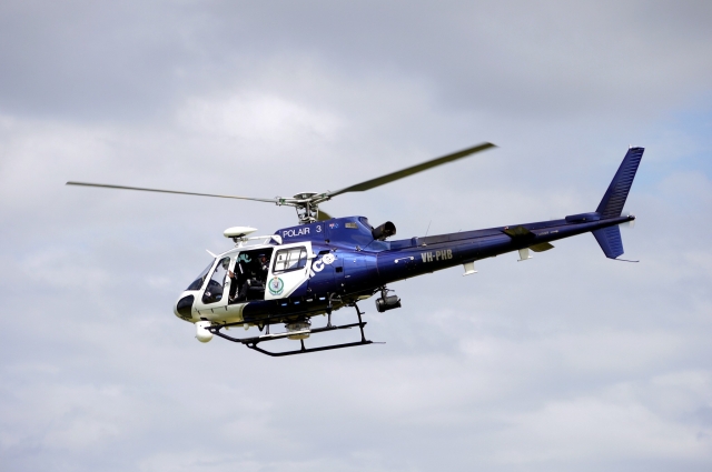 Blue and white helicopter flying over the coast