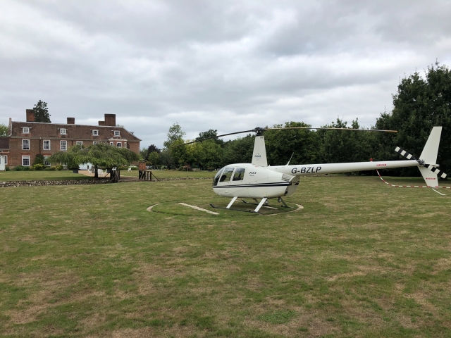 White helicopter landed and stone house in front of it