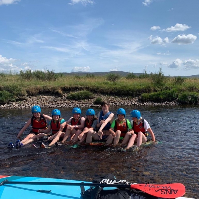  Junge Mädchen und Jungen mit roten Schwimmhilfen bereiten sich auf das Rafting vor