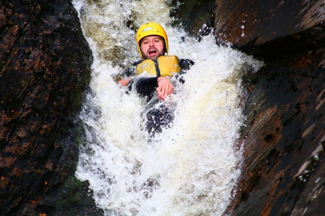 Uomo che indossa il casco giallo che fa canyoning 