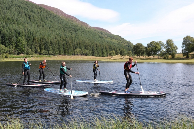  Zwei Männer tragen grüne und orange Auftriebshilfen beim Paddleboarding 