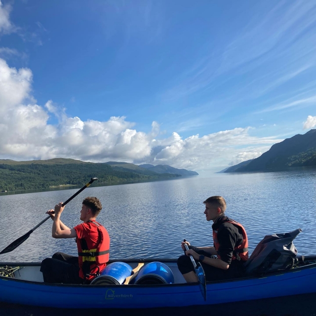  Deux jeunes garçons portant des aides à la flottabilité rouges souriant et faisant du canoë 