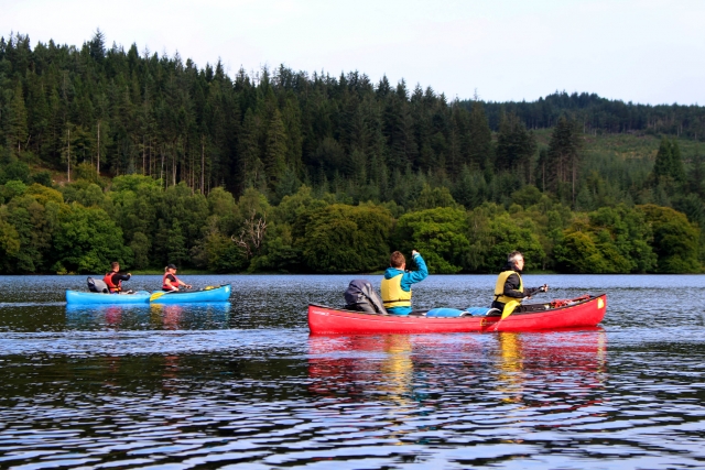 Two men, wearing yellow buoyancy aids, and a woman and a man, wearing red buoyancy aids, kayaking around Great Glen