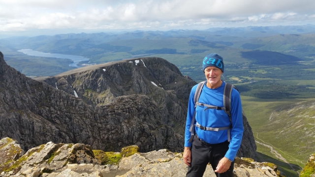  Uomo sorridente che indossa una maglietta blu durante la sua sessione di arrampicata sul Ben Nevis