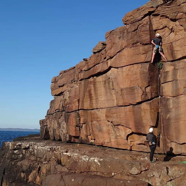  Due ragazzi che indossano i caschi bianchi e le magliette nere durante il corso di arrampicata 