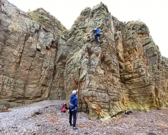  Due persone che indossano i caschi bianchi e i maglioni blu durante il corso di arrampicata 