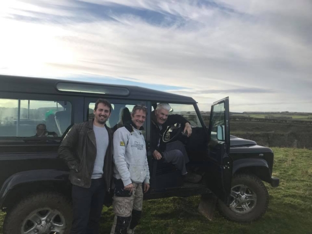  Three men wearing white and black sweaters smiling and about to drive a 4x4 as part of their multi-adventure session 