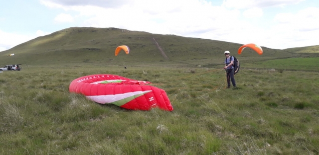  Aventurero con casco amarillo y a punto de volar con un parapente rojo 