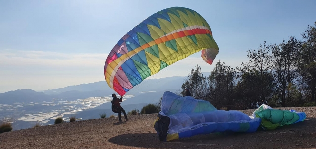  Hombre vistiendo un suéter negro a punto de hacer parapente en un colorido parapente