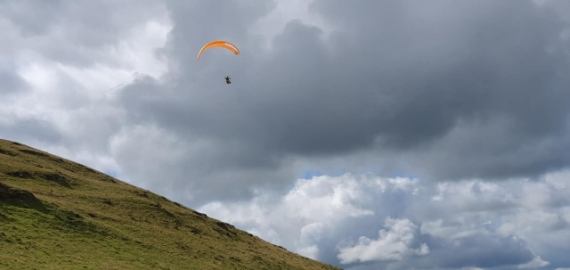  Niño volando con parapentes naranjas en el cielo y la playa debajo 