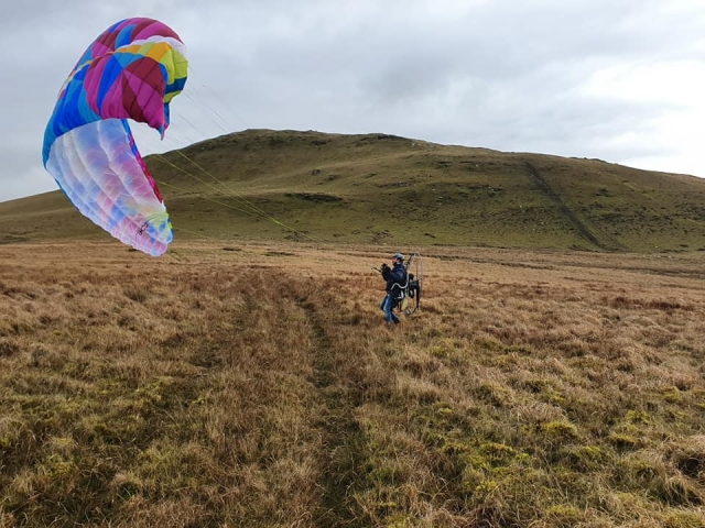  Niño con casco azul corriendo para volar con parapentes de colores