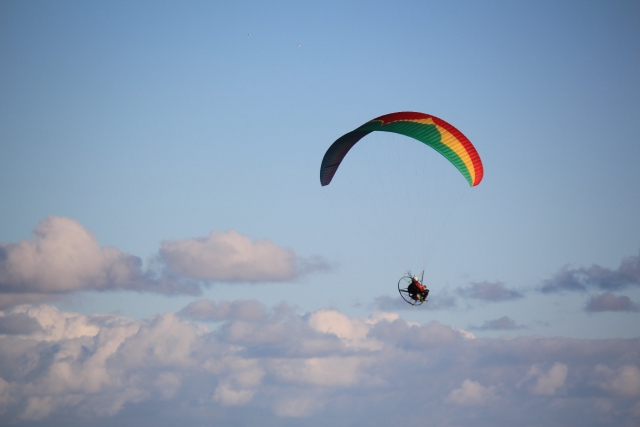  Person fliegt mit grünem, gelbem und rotem Motorschirm 