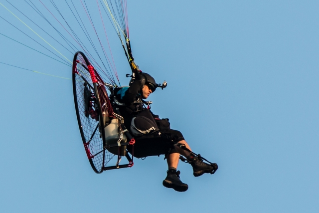  Mädchen mit schwarzem Helm und schwarzer Kleidung fliegt mit Motorschirm 