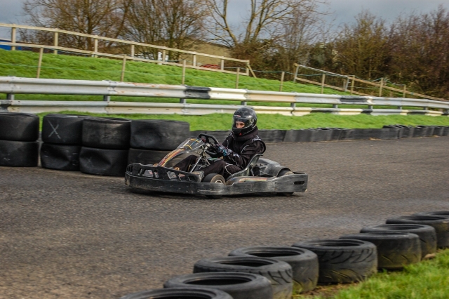 Garçon portant une combinaison de conduite noire et un casque s'amusant avec son entraînement de karting 