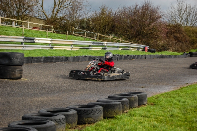  Jeune garçon portant une combinaison de conduite rouge et un casque noir de karting 