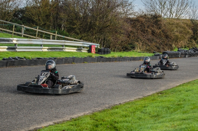  Tres niños con cascos y trajes de conducción negros durante la carrera del Gran Premio 
