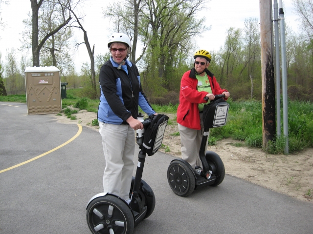  Uomo che indossa casco bianco e giacca blu e donna che indossa casco giallo e giacca rossa che fanno un giro per il parco in segway 