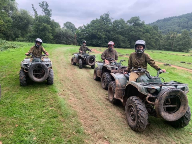  4 amis portant des combinaisons de camouflage et des casques noirs faisant du quad