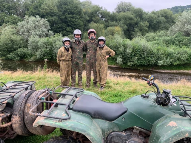 Deux garçons et deux filles portant des casques noirs et une tenue de camouflage sur le point de commencer leur séance de quads 