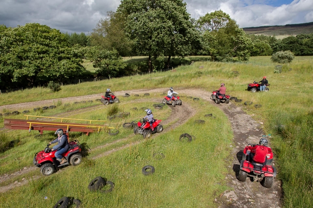  Avventurieri indossano caschi e guidano quad rossi in giro per il bosco 