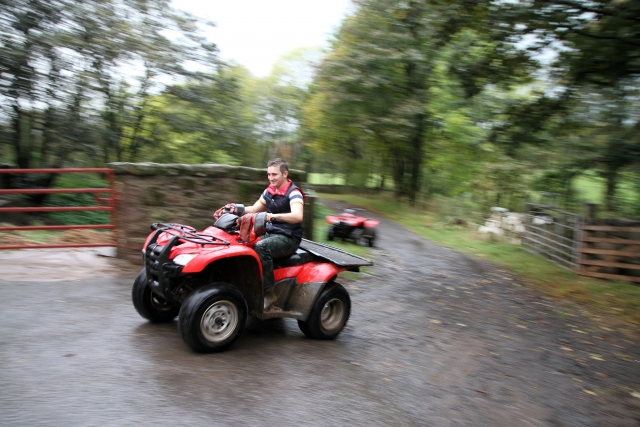  Jeune garçon conduisant un quad rouge autour de la forêt 