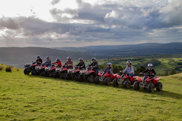 Les enfants se préparent à conduire les quads rouges autour de la montagne 