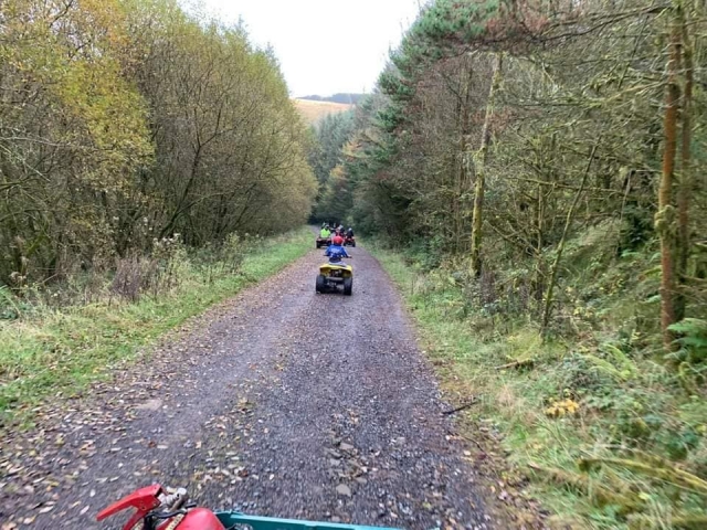  Les jeunes conduisent des quads rouges autour de la forêt et portent des casques et des combinaisons de conduite 