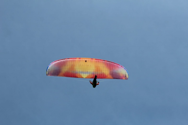  Aventurier portant un costume rouge survolant avec un parapente coloré 