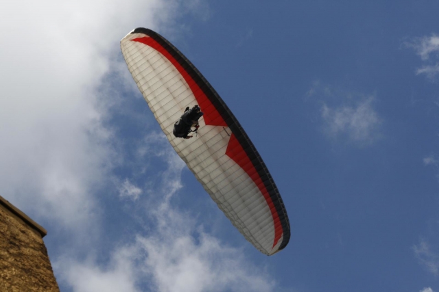  Person fliegt über die Küste, Klippe im Hintergrund und mit weißem und rotem Gleitschirm 