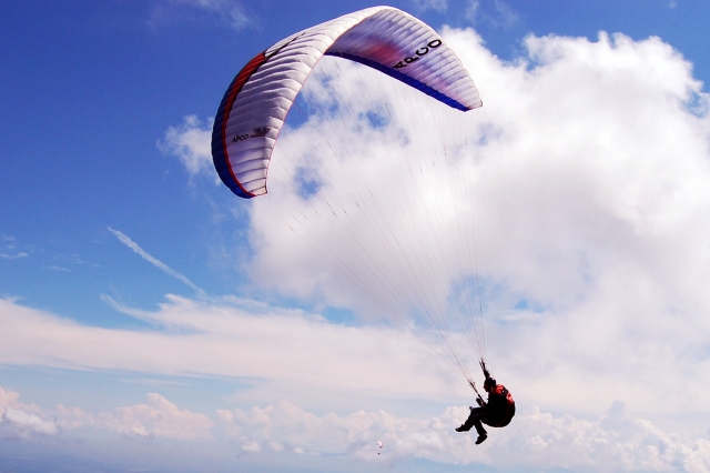  Person fliegt mit weißem und rotem Gleitschirm 