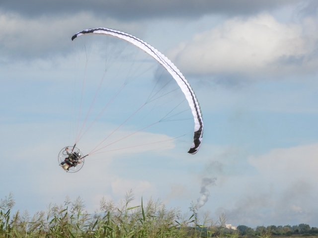  Fliegen mit weißem und blauem Gleitschirm über der Küste 