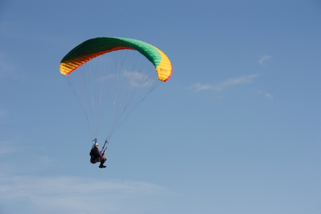  Abenteurer verwandelt sich in einen Piloten mit grün-gelb-orangefarbenem Gleitschirm 