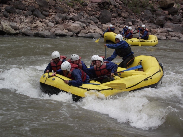  Due gruppi che indossano aiuti al galleggiamento rossi, mute blu e fanno rafting intorno al fiume
